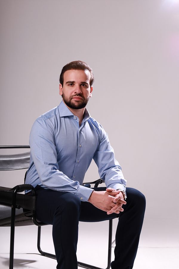 Dr. Nelson Seixas Jr. sentado, de camisa azul