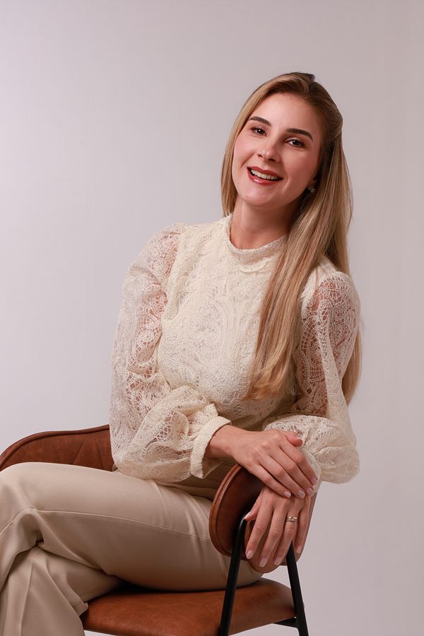 Dra. Mariana Borduchi sorrindo, sentada, de blusa de renda