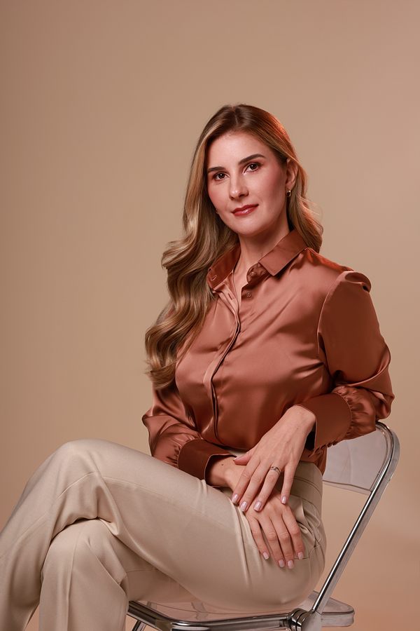 Dra. Mariana Borduchi sentada, de blusa acetinada