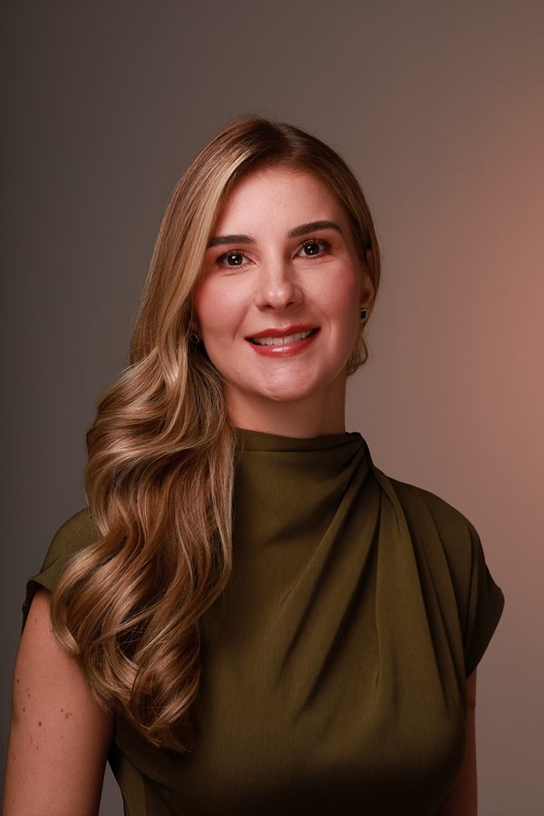 Dra. Mariana Borduchi sorrindo, de vestido verde-oliva